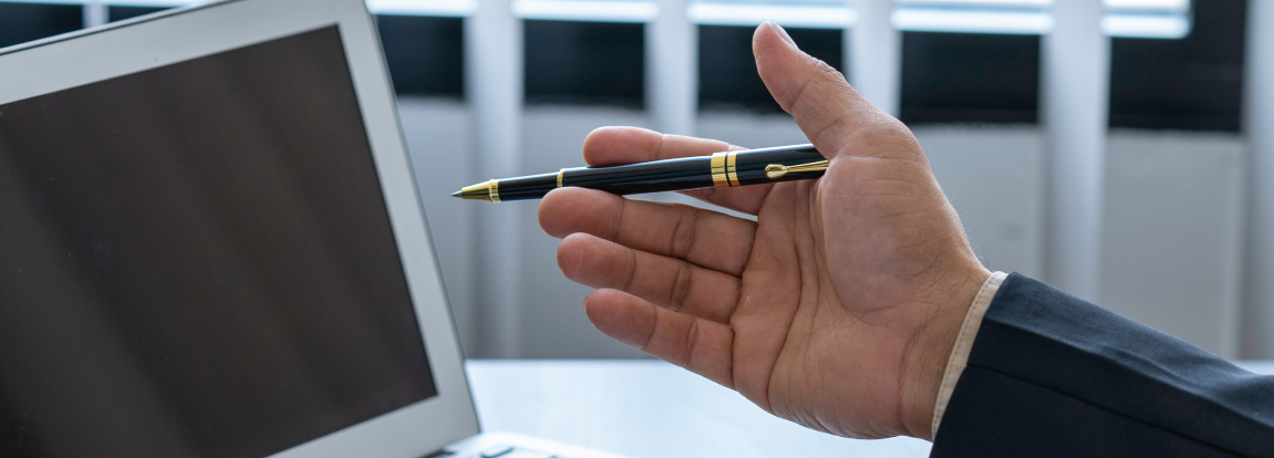 パソコンとペンを持つ手の写真