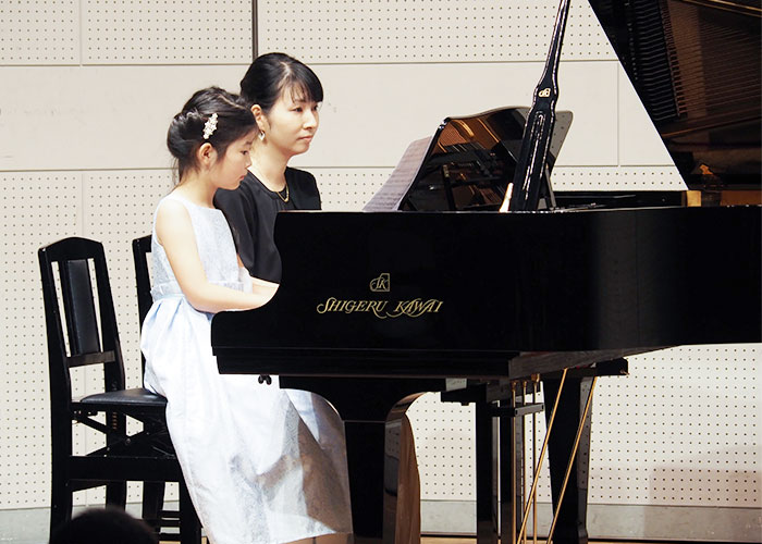 女の子とお母さんとのピアノ連弾の発表の写真